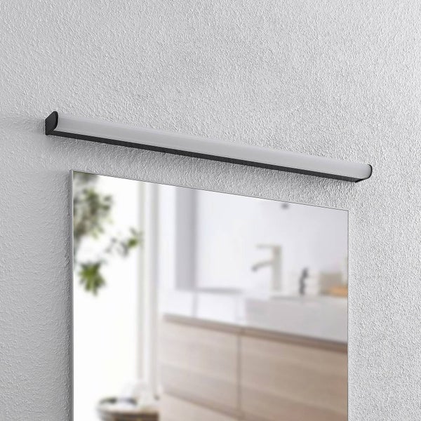 Längliche LED-Badezimmerleuchte über einem Spiegel, schwarzes Gehäuse mit weißem Diffusor.