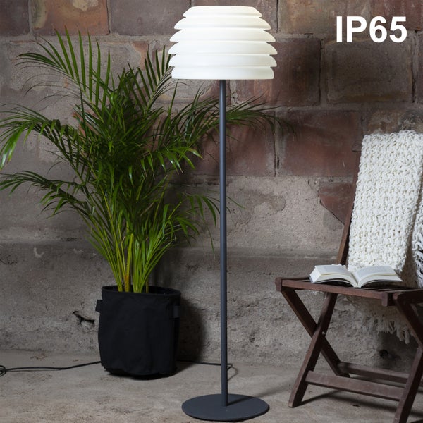 Stehlampe mit Schutzart IP65 neben einer Zimmerpflanze und einem Klapptisch mit Buch