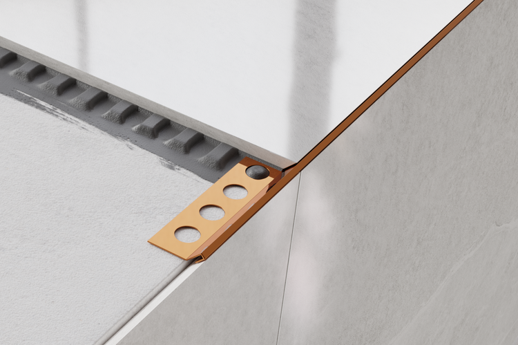 Fliesenprofil aus Metall mit runden Aussparungen an einer gefliesten Ecke