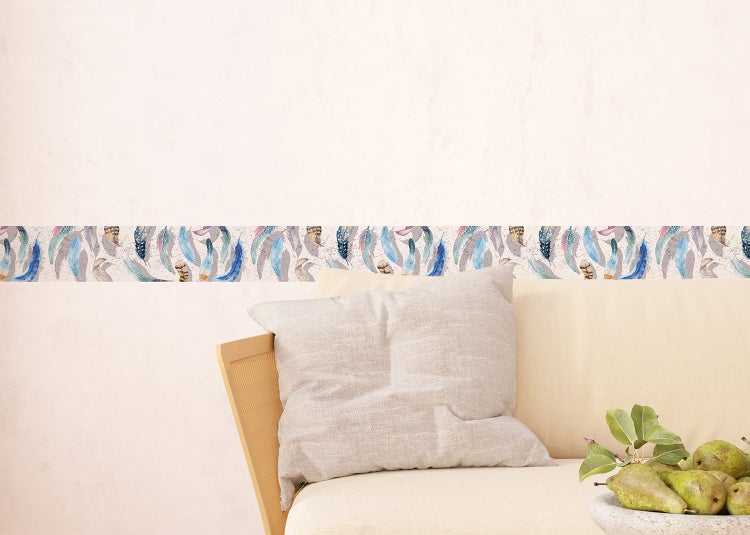 Tapetenbordüre mit Federmuster an einer hellen Wand über einem Sofa mit Kissen.