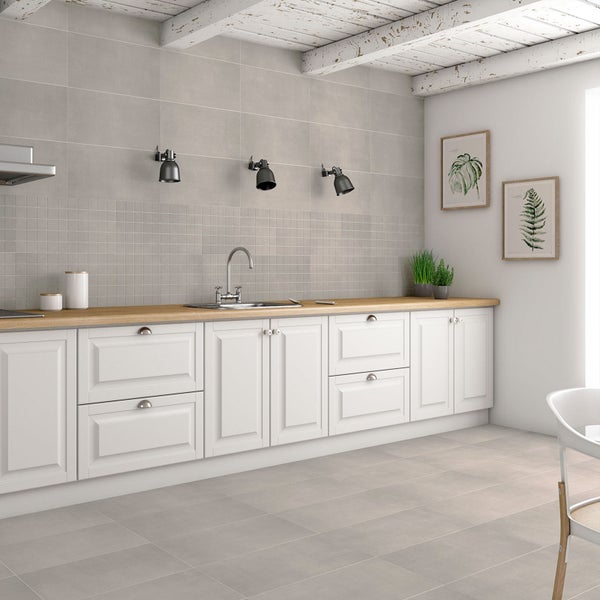 Moderne Küche mit weißen Schränken, Holzarbeitsplatte, grauen Wand- und Bodenfliesen sowie schwarzen Wandleuchten.