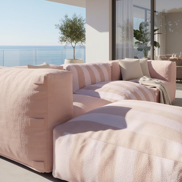 Modernes, helles Lounge Sofa mit Streifenmuster auf einer geräumigen Terrasse mit Meerblick und Olivenbaum.
