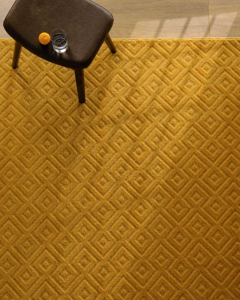 Teppich mit geometrischem Muster auf Holzboden, weiche Textur mit offenem Buch und Kissen.