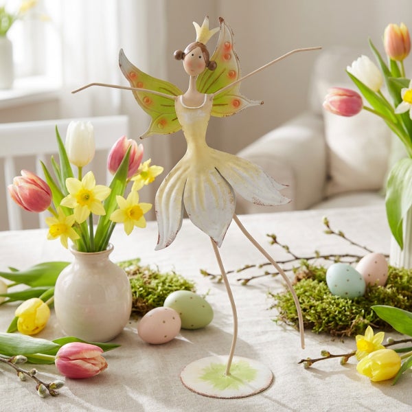 Dekorative Metallfigur einer Fee als Tischdekoration für Ostern mit Tulpen und Narzissen