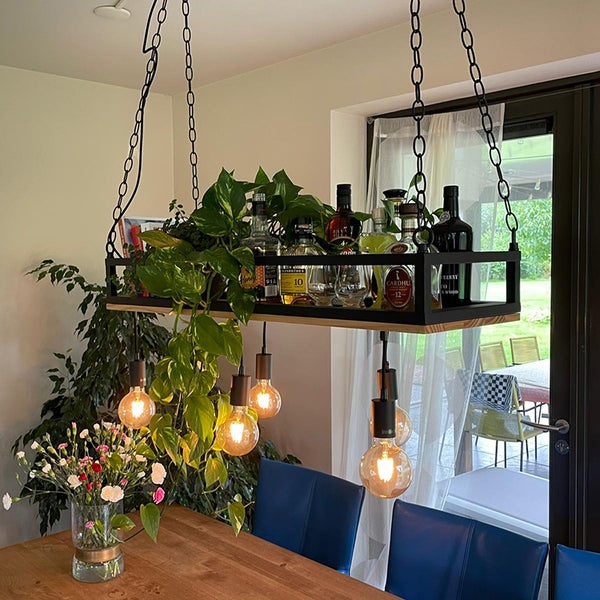 Hängelampe über einem Esstisch mit Pflanzen und Flaschen dekoriert