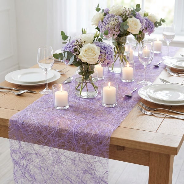 Festlich gedeckter Esstisch mit lila Tischläufer aus netzartigem Material, Blumenvasen mit Rosen und Hortensien sowie brennenden Stumpenkerzen.