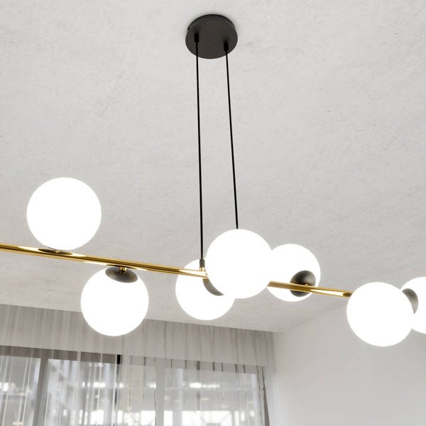 Moderne Pendelleuchte mit mehreren Glaskugeln an einer goldenen Stange