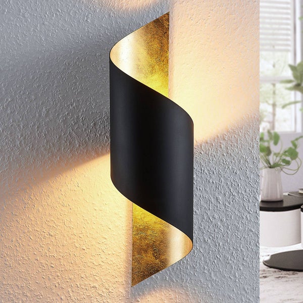 Moderne spiralförmige Wandleuchte in Schwarz mit goldfarbener Innenseite, strahlt warmes Licht auf eine strukturierte Wand.