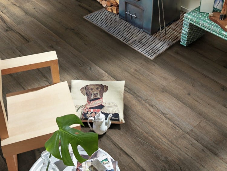 Wohnraum mit rustikalem Laminatboden in Holzoptik, Kaminofen auf einer Bodenplatte und modernen Wohnaccessoires.