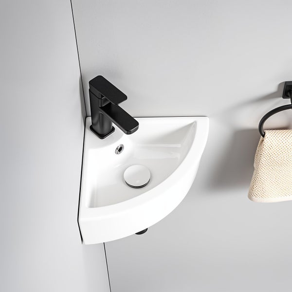 Weißes Keramik Eckwaschbecken mit schwarzer Armatur in einer Badezimmerecke montiert.