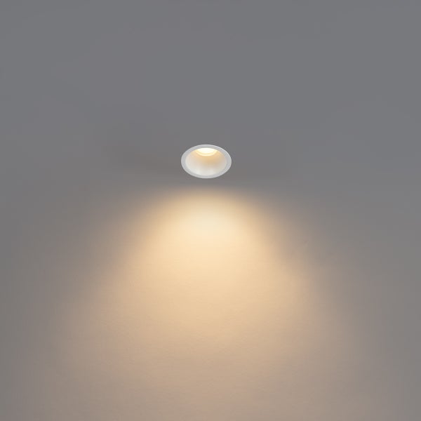 Einbaustrahler rund weiß, eingeschaltet mit warmweißem Lichtkegel.
