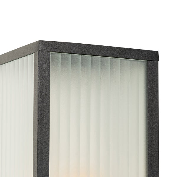 Detailansicht der oberen Ecke einer rechteckigen Außenwandleuchte mit strukturiertem Metallgehäuse und geriffelten Glaseinsätzen.