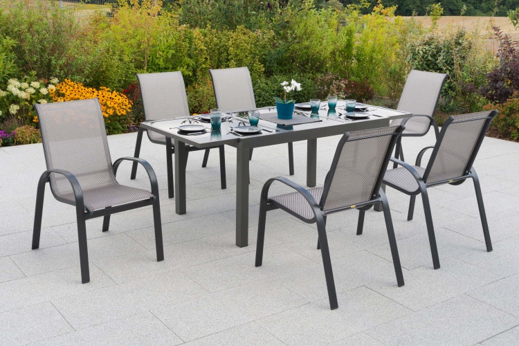 Gartenszene mit Esstisch aus Glas und sechs Stühlen mit Textilbespannung