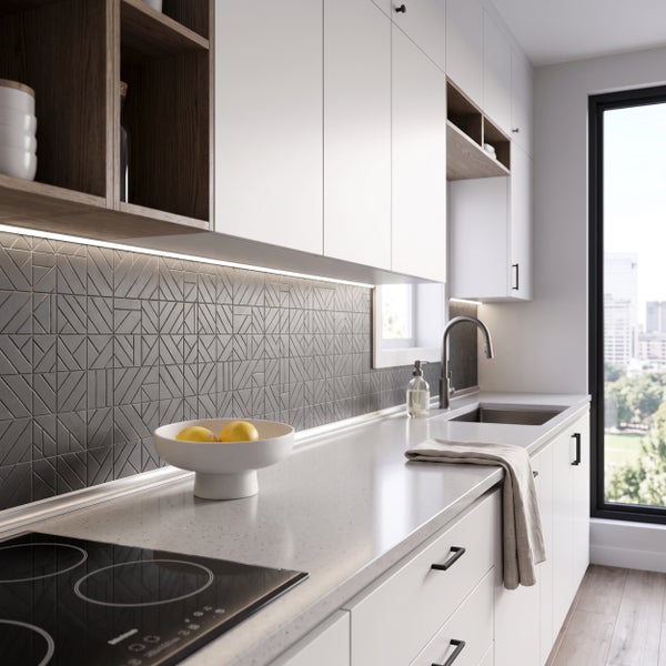Moderne helle Küche mit Küchenzeile, gemustertem Fliesenspiegel, Induktionskochfeld und Arbeitsplatte in minimalistischem Design.