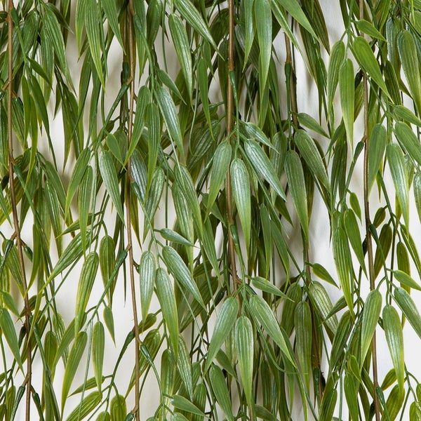 Künstlicher Zweig mit vielen kleinen, gezackten grünen Blättern.