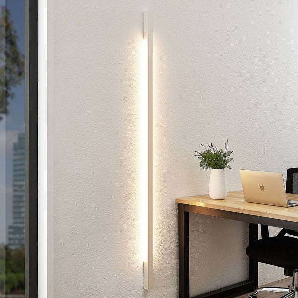 Vertikale LED-Wandleuchte im minimalistischen Design, montiert an einer Wand neben einem Schreibtisch in einem hellen, organisierten Arbeitsbereich.
