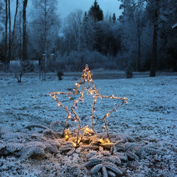 Leuchtender Stern im Garten mit Winterlandschaft im Hintergrund