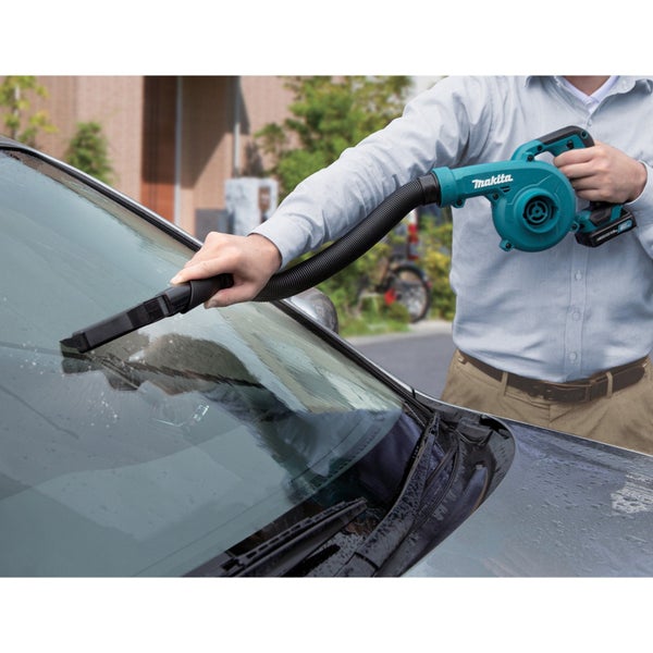Eine Person trocknet mit einem Makita Laubbläser die Windschutzscheibe eines Autos.