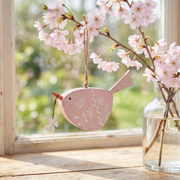 Dekorative Holzvogel zum Aufhängen mit Blumenmuster und kleiner Blüte im Schnabel, als Frühlingsdekoration geeignet.