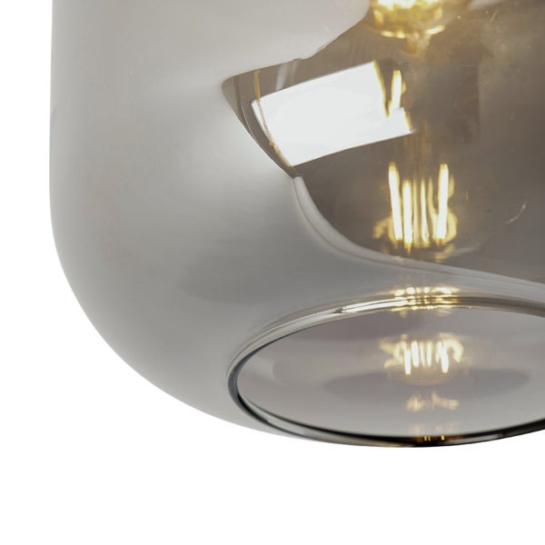 Nahaufnahme eines runden Lampenschirms aus Glas mit brennendem Leuchtmittel im Inneren.