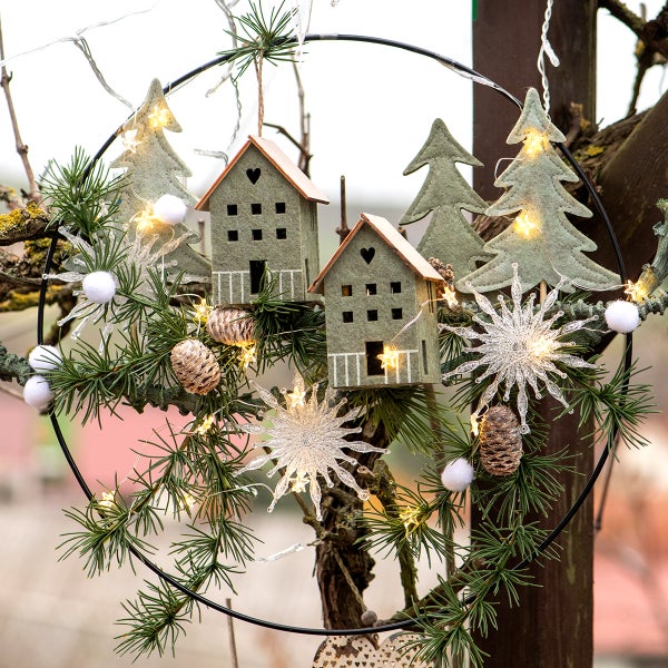 Dekorativer Türkranz mit Häusern, Tannenbäumen, Tannenzapfen, Schneeflocken, Kugeln und Lichterkette