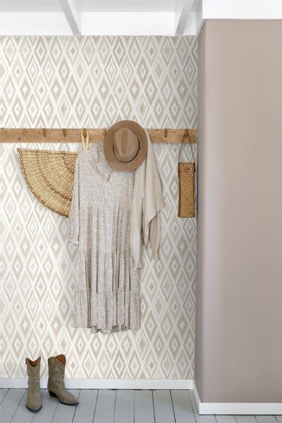 Raumansicht mit gemusterter Tapete, Garderobe mit Kleidungsstücken und Stiefeln