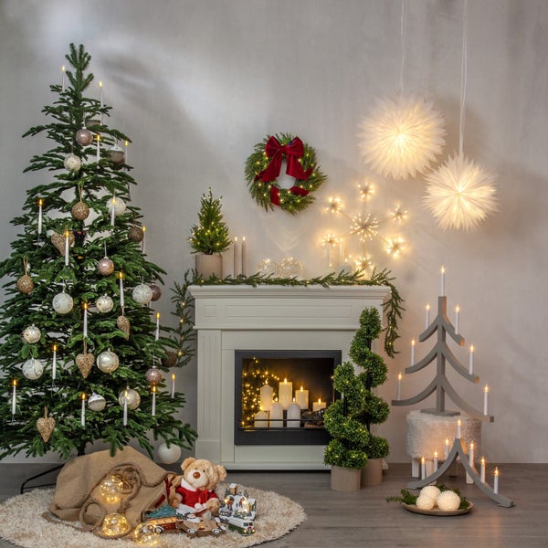 Weihnachtliche Dekoration mit Tannenbaum, Kamin, Weihnachtsstern und Beleuchtung für eine festliche Atmosphäre