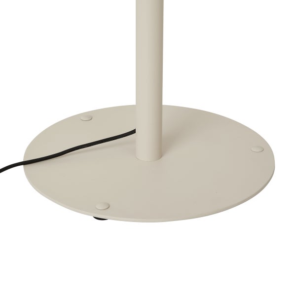 Runder beiger Metallsockel einer Stehleuchte mit Standrohr und schwarzem Kabel.