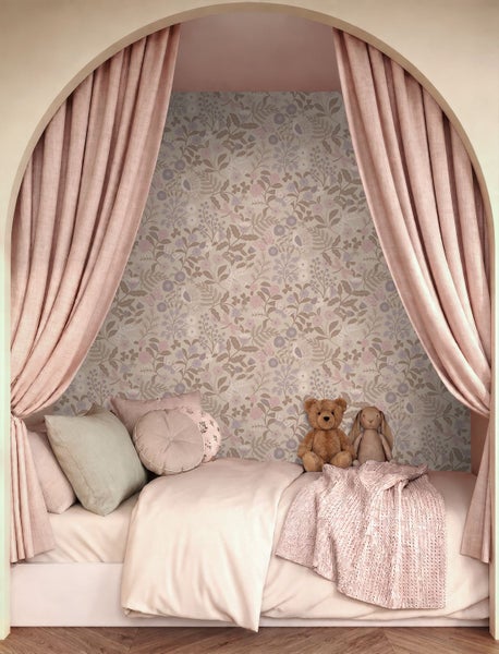 Gemütliche Kinderzimmer-Nische mit floral gemusterter Tapete, gerafften Vorhängen, Bett mit verschiedenen Kissen und Stofftieren.
