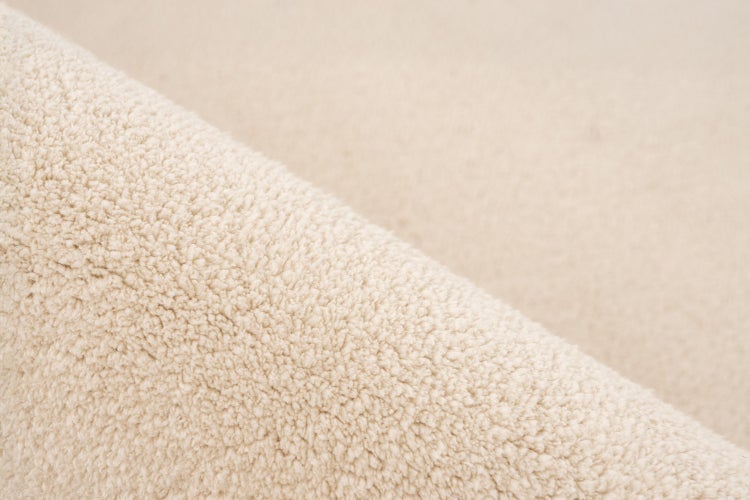 Nahaufnahme der Textur eines Teppichs mit weichem Flor und dichter Struktur.