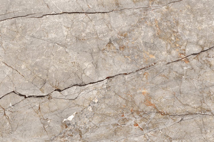 Nahaufnahme einer grauen Marmorfliese mit dunklen und hellen Maserungen.