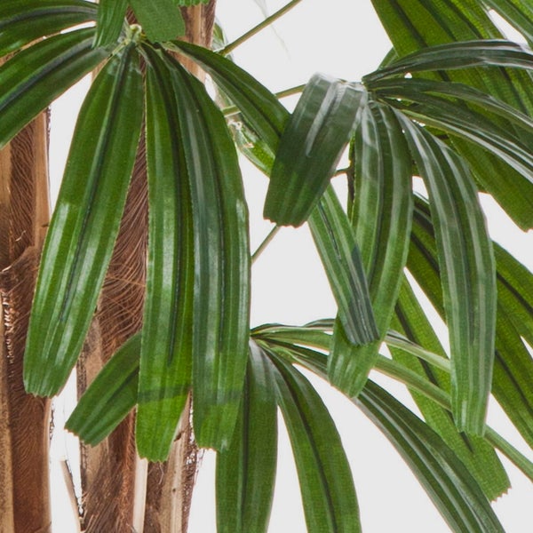 Detailansicht einer künstlichen Palme mit grünen Blättern und strukturiertem braunem Stamm.