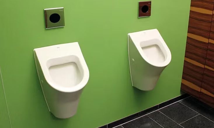 Zwei wandhängende Urinale mit elektronischer Spülbetätigung montiert an einer Wand in einer öffentlichen sanitären Einrichtung.
