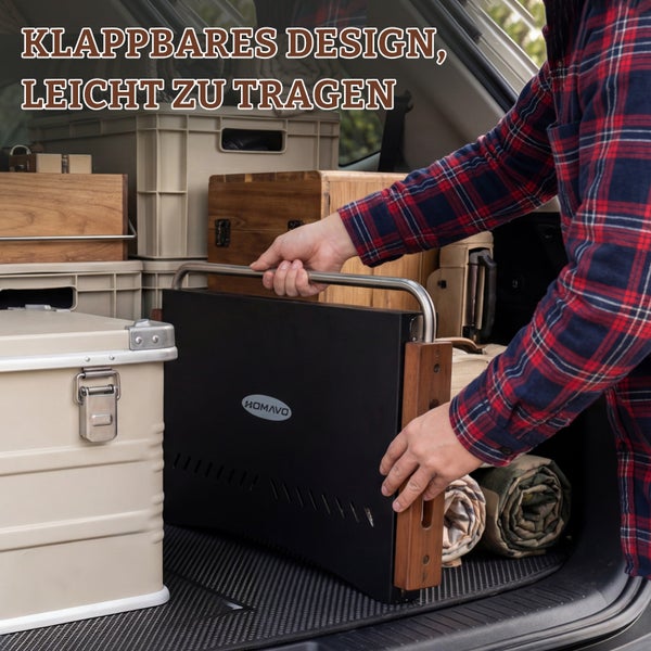 Person hebt einen flach zusammengeklappten schwarzen tragbaren Grill mit ROMAVO Logo, Metallgriff und Holzelementen aus einem Auto-Kofferraum.