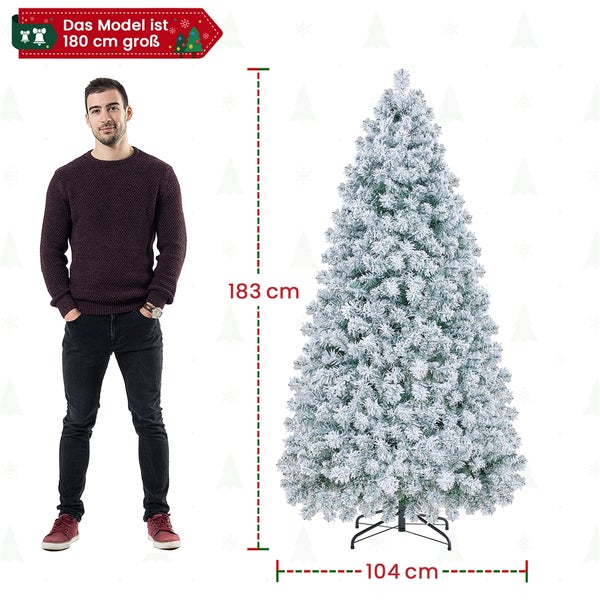 Abbildung eines 183 Zentimeter hohen, beschneiten künstlichen Weihnachtsbaums mit Ständer und Maßangaben neben einer Person.