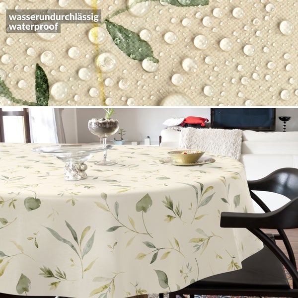 Runde wasserundurchlässige Tischdecke mit Blättermotiv in einem hellen Zimmer, Detailansicht zeigt abperlende Wassertropfen auf dem Material.