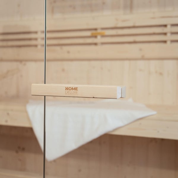 Saunatürgriff aus Holz mit Home Deluxe Logo an einer Glasfront im Innenbereich einer Sauna