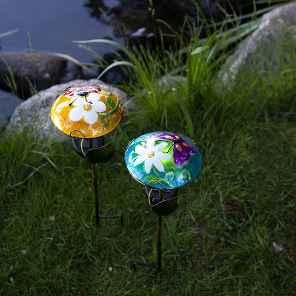 Zwei Gartenstecker mit Blumen- und Schmetterlingsmotiven im Gras