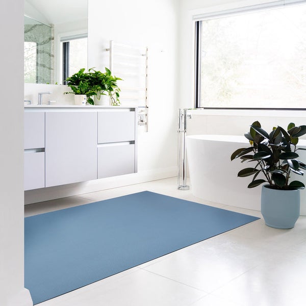 Badezimmer mit blauem Teppich, Waschbecken, Badewanne und Zimmerpflanzen