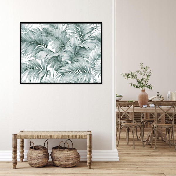 Wandbild mit Palmenblattmotiv in schwarzem Rahmen über einer Sitzbank mit geflochtenem Sitz und zwei darunter stehenden Weidenkörben.