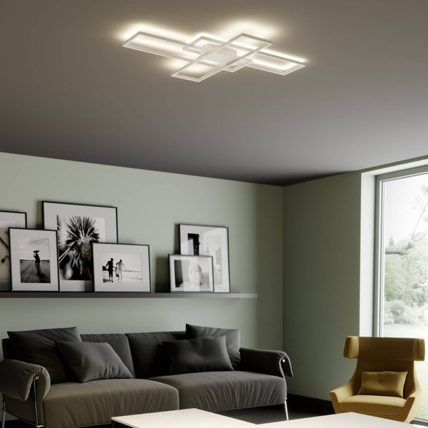 Moderne LED-Deckenleuchte mit überlappenden rechteckigen Rahmen in einem Wohnzimmer mit Sofa, Sessel und Bilderwand.