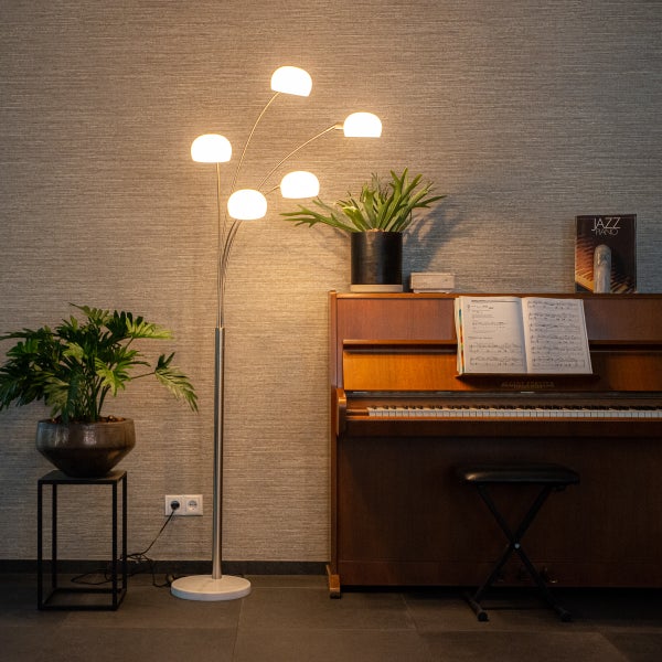 Stehlampe mit fünf Leuchten neben einem Klavier und einer Zimmerpflanze