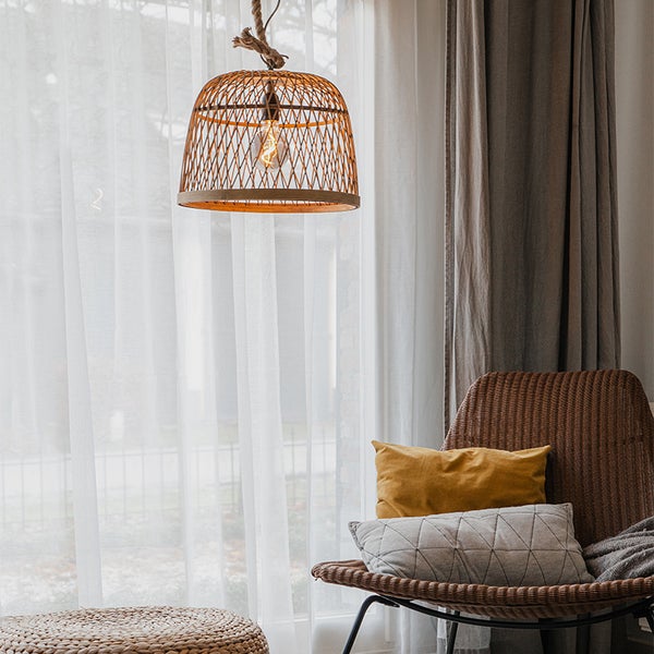 Dekorative Wohnszene mit Korblampe, Sessel und Kissen