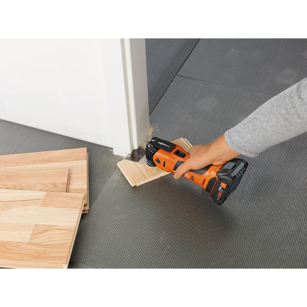 Fein Akku Multimaster Multitool schneidet einen Holzboden bei einer Türzarge zu.