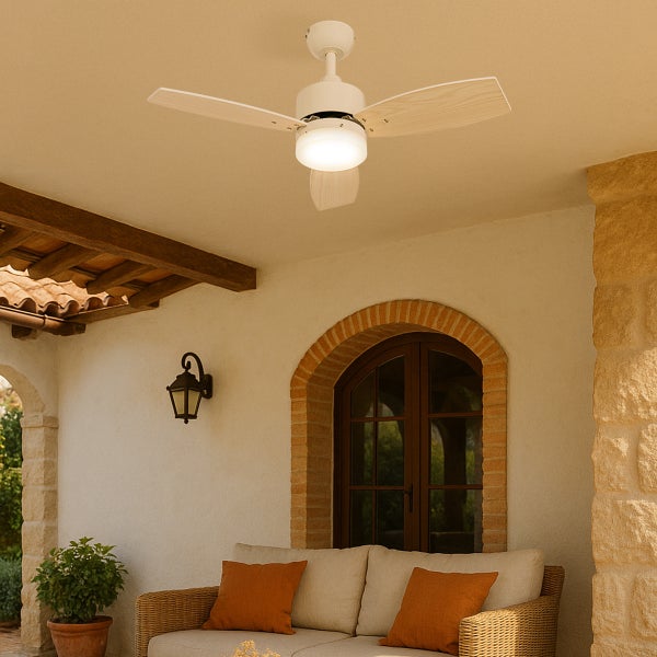 Deckenventilator mit drei hellen Holzflügeln und integrierter Beleuchtung auf einer überdachten Terrasse mit Korbmöbeln und Steinwand.