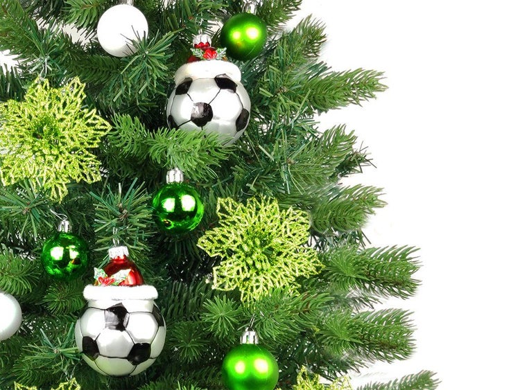 Weihnachtsbaum geschmückt mit glitzernden Sternen und Weihnachtskugeln in Form von Fußbällen und klassischen Kugeln
