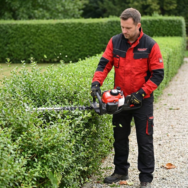 Mann schneidet Hecke mit einer Heckenschere.