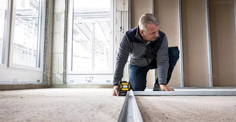 Handwerker richtet Ständerwand im Trockenbau mit einem Kreuzlinienlaser aus.