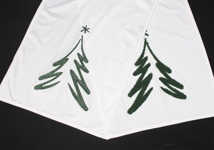 Weißer Baumteppich mit grünen Weihnachtsbäumen.