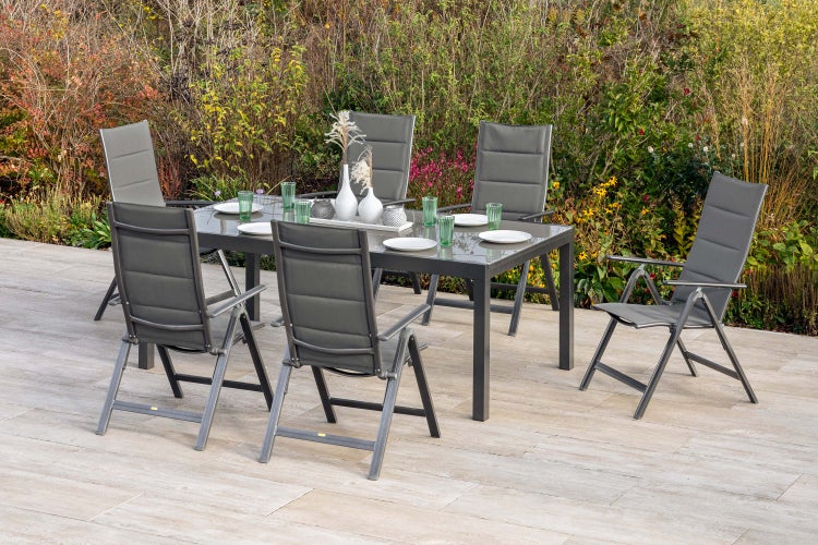 Gartenmöbelset mit Tisch, Stühlen und Dekoration auf einer Terrasse vor einem Garten